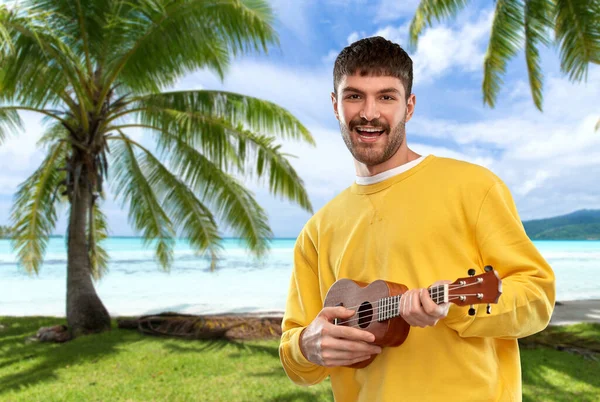 Sorridente giovane uomo che suona la chitarra ukulele — Foto Stock