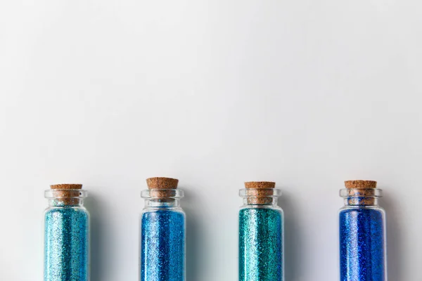 Голубые блестки в бутылках на белом фоне — стоковое фото