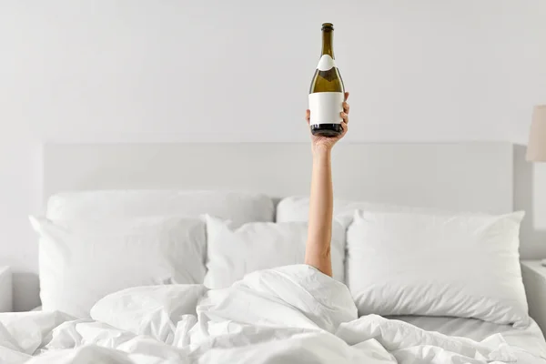Mão de mulher deitada na cama com champanhe — Fotografia de Stock