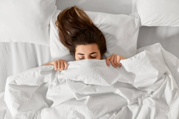 Mujer acostada en la cama debajo de una manta blanca o edredón —  Fotos de Stock