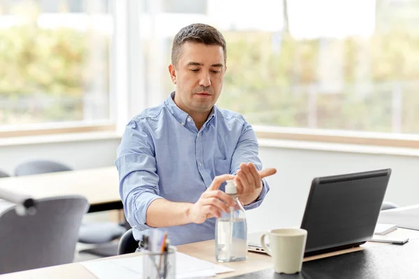 Homme utilisant un désinfectant pour les mains au bureau à domicile — Photo