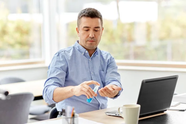 Homme utilisant un désinfectant pour les mains au bureau à domicile — Photo