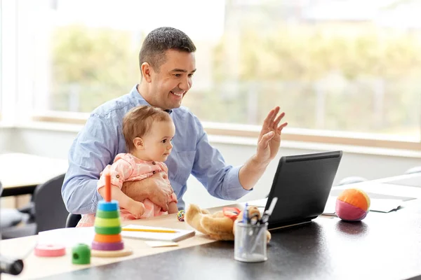 自宅のノートパソコンで働く赤ちゃんを持つ父親は — ストック写真
