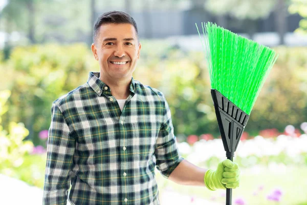 Gelukkige man van middelbare leeftijd met bezem in de tuin — Stockfoto