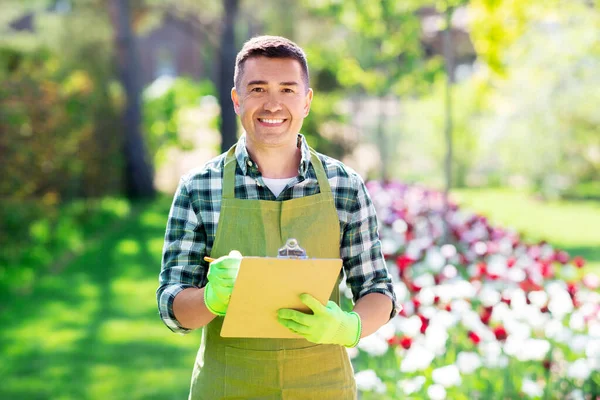 Glücklicher Mann mit Klemmbrett im Sommergarten — Stockfoto