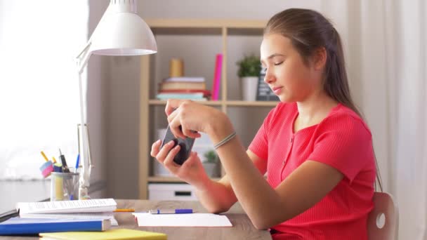 Девушка со смартфоном отвлекает от домашней работы — стоковое видео