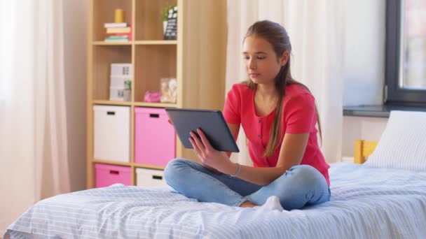 Menina sorridente com tablet pc sentado na cama em casa — Vídeo de Stock