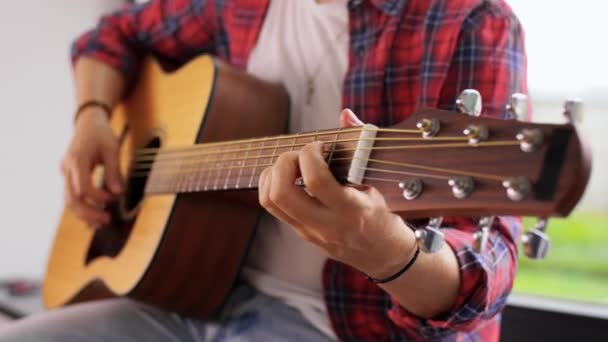 Joven tocando guitarra sentado en el alféizar de la ventana — Vídeos de Stock