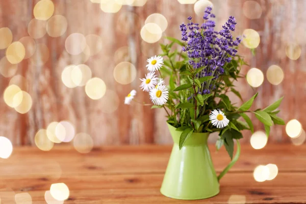 Kräuter- und Blumenstrauß in grünem Krug auf dem Tisch — Stockfoto