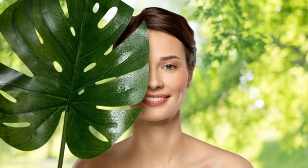 Schöne junge Frau mit grünem Monstera-Blatt — Stockfoto