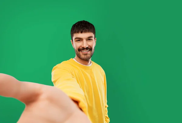 Счастливый молодой человек в желтой футболке делает селфи — стоковое фото