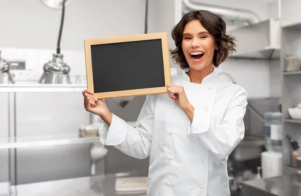 Cocinera sonriente sosteniendo pizarra negra —  Fotos de Stock