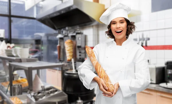 Glad kvinnlig kock med franskt bröd eller baguette — Stockfoto