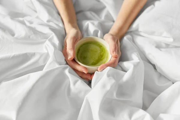 Manos de mujer con taza de té matcha en la cama —  Fotos de Stock