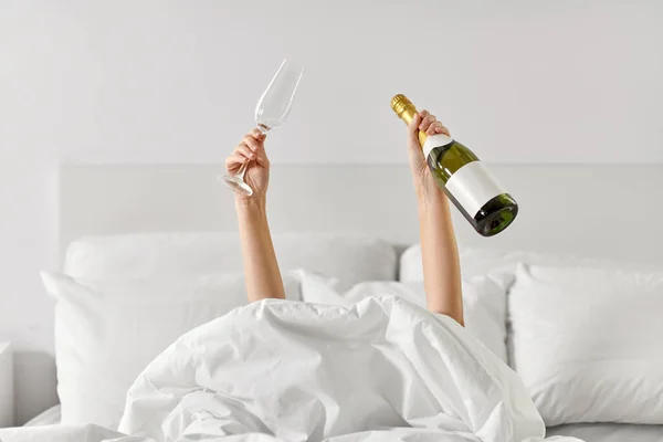 Руки жінки лежать в ліжку з шампанським — стокове фото