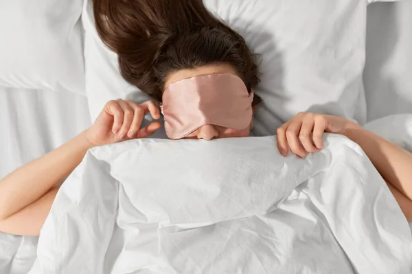 Mujer con máscara de dormir ojo en la cama debajo de la manta —  Fotos de Stock
