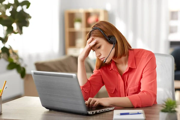 Mulher triste com fone de ouvido e laptop trabalhando em casa — Fotografia de Stock