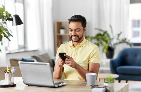 Glücklicher indischer Mann mit Smartphone im Home Office — Stockfoto