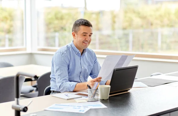 Homme avec ordinateur portable et papiers travaillant au bureau à domicile — Photo