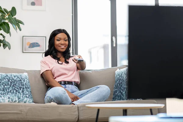 Gelukkig Afrikaans amerikaanse vrouw kijken tv thuis — Stockfoto