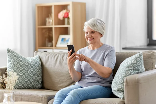 Gelukkig senior vrouw met smartphone thuis — Stockfoto