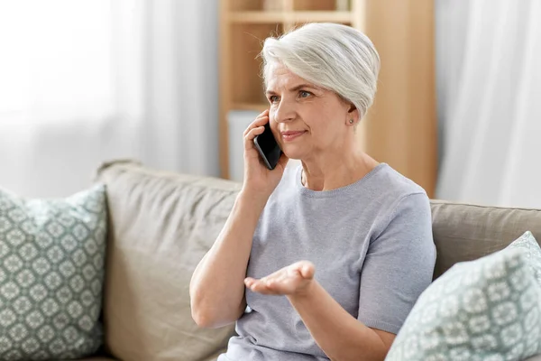 Пожилая женщина звонит на смартфон дома — стоковое фото