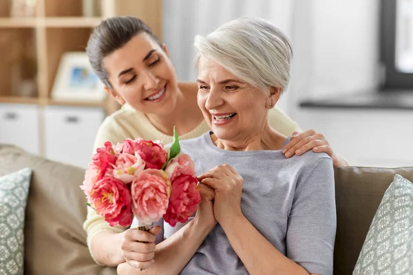 Volwassen dochter geven bloemen naar oud moeder — Stockfoto
