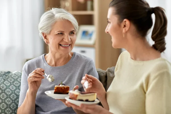 Vecchia madre e figlia adulta mangiare torta a casa — Foto Stock
