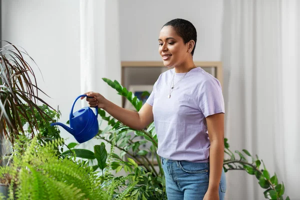 Mujer afroamericana regando plantas en casa —  Fotos de Stock