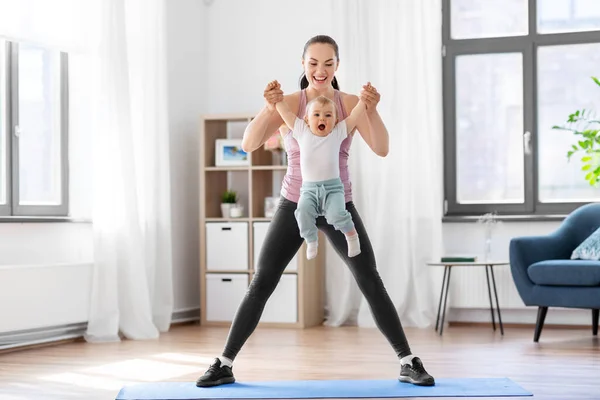 Madre feliz con el pequeño bebé haciendo ejercicio en casa —  Fotos de Stock