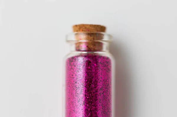 Růžové třpytky v láhvi přes bílé pozadí — Stock fotografie