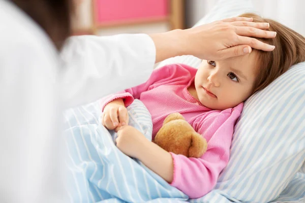 Doctor measuring sick girls temperature at home — Stock Photo, Image