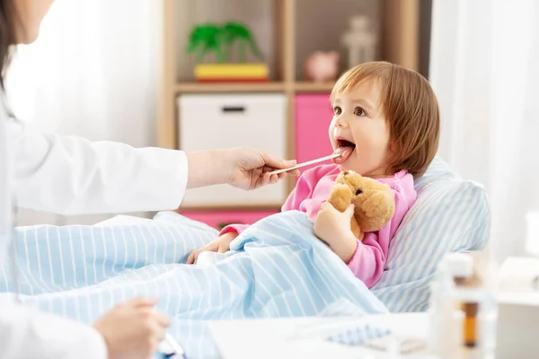 医者は家で病気の女の子の喉をチェック — ストック写真
