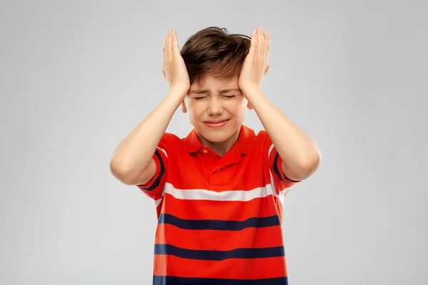 Menino estressado em vermelho polo t-shirt tendo dor de cabeça — Fotografia de Stock
