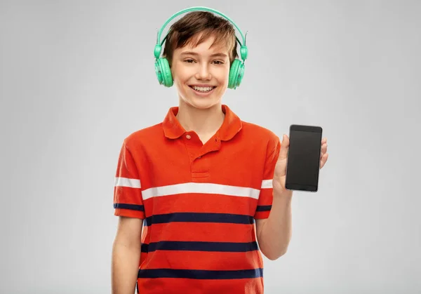 Pojke i hörlurar lyssna på musik på smartphone — Stockfoto