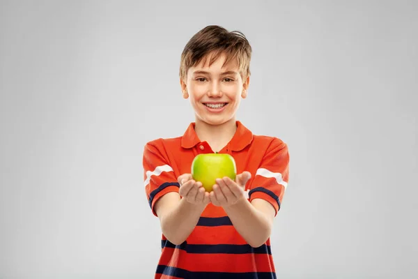 Porträtt av glad leende pojke som håller grönt äpple — Stockfoto