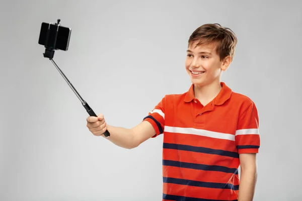 Menino tirando foto com smartphone no pau selfie — Fotografia de Stock