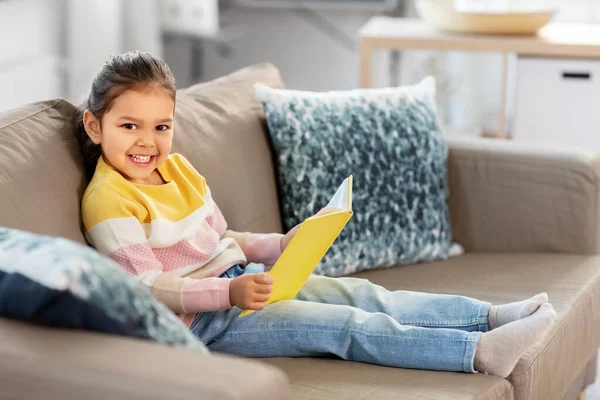 快乐的微笑着的小女孩在家里看书 — 图库照片