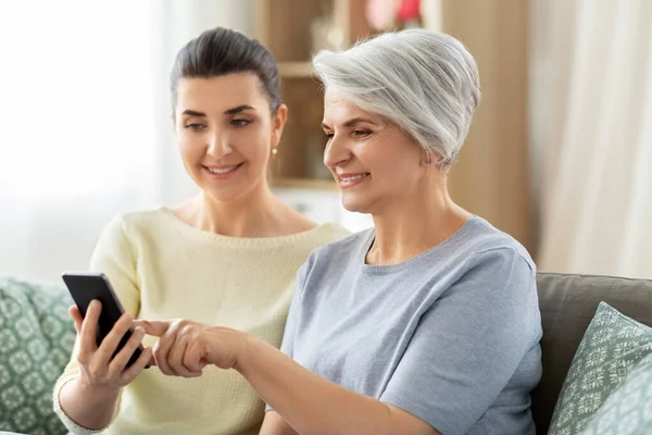 Dochter en senior moeder met smartphone thuis — Stockfoto