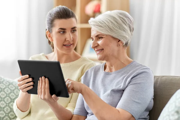 Figlia e madre anziana con tablet pc a casa — Foto Stock