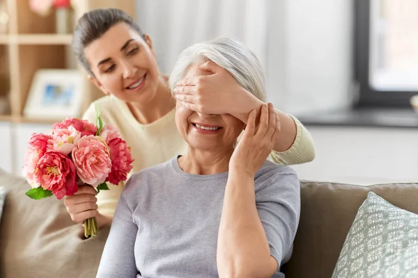 Figlia adulta dando fiori alla vecchia madre — Foto Stock