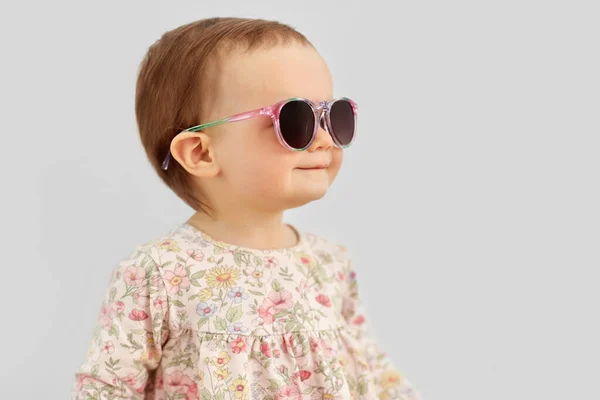 Щаслива маленька дівчинка в сонцезахисних окулярах над сірим — стокове фото