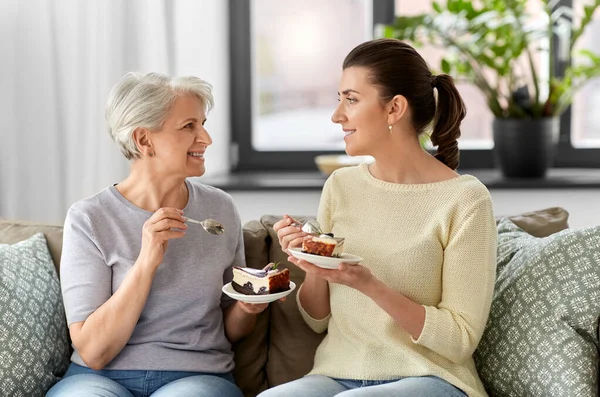 Стара мати і доросла дочка їдять торт вдома — стокове фото