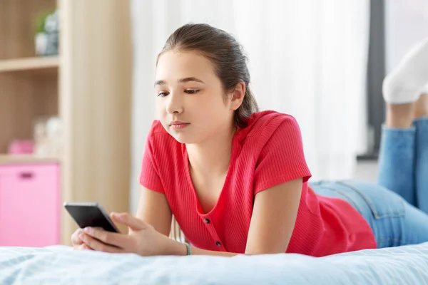 Trauriges Teenager-Mädchen, das zu Hause auf dem Smartphone SMS schreibt — Stockfoto