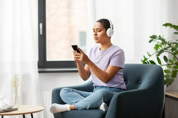 Kvinna med smartphone lyssnar på musik hemma — Stockfoto