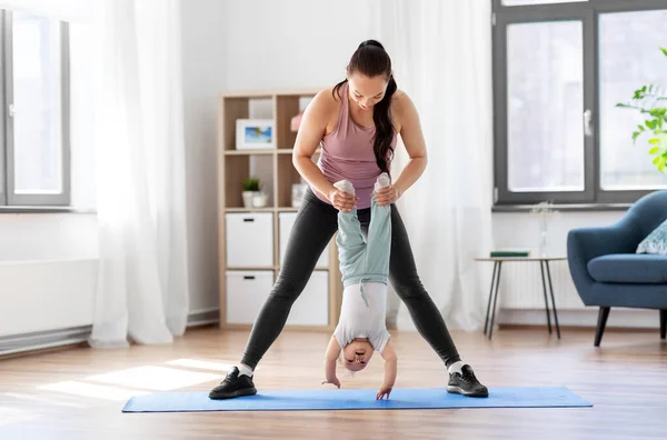Mutlu bir anne ve küçük bir bebek evde egzersiz yapıyor. — Stok fotoğraf