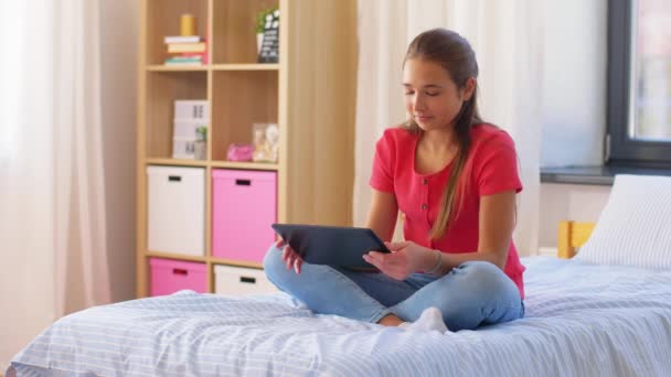 Menina sorridente com tablet pc sentado na cama em casa — Vídeo de Stock