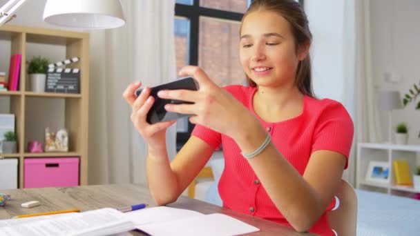 Mädchen mit Smartphone lenkt von Hausaufgaben ab — Stockvideo