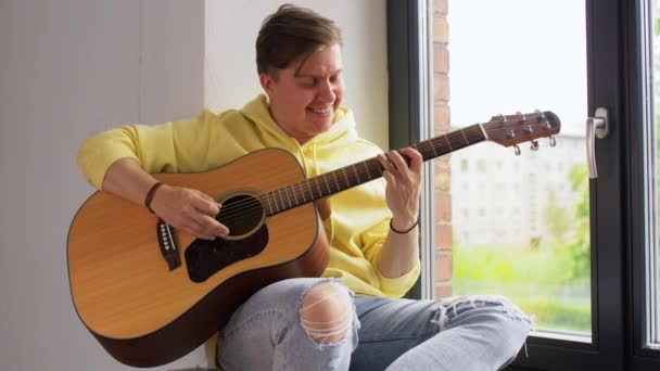 Giovane uomo che suona la chitarra seduto sul davanzale della finestra — Video Stock