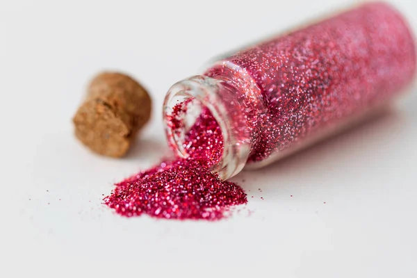 Roze rode glitters gegoten uit kleine glazen fles — Stockfoto